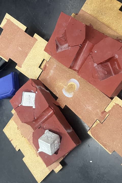 Two pewter dice in their mold