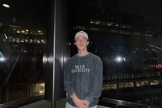 Derek in front of a nighttime city skyline