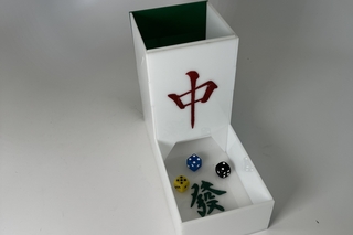 a white and green dice tower engraved with red and green Chinese characters for playing the game Mahjong