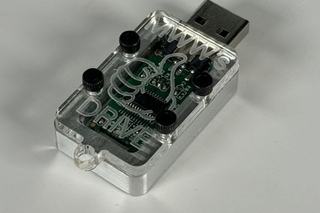 A transparent flash drive case with the engraving "MWW's Thumb Drive"